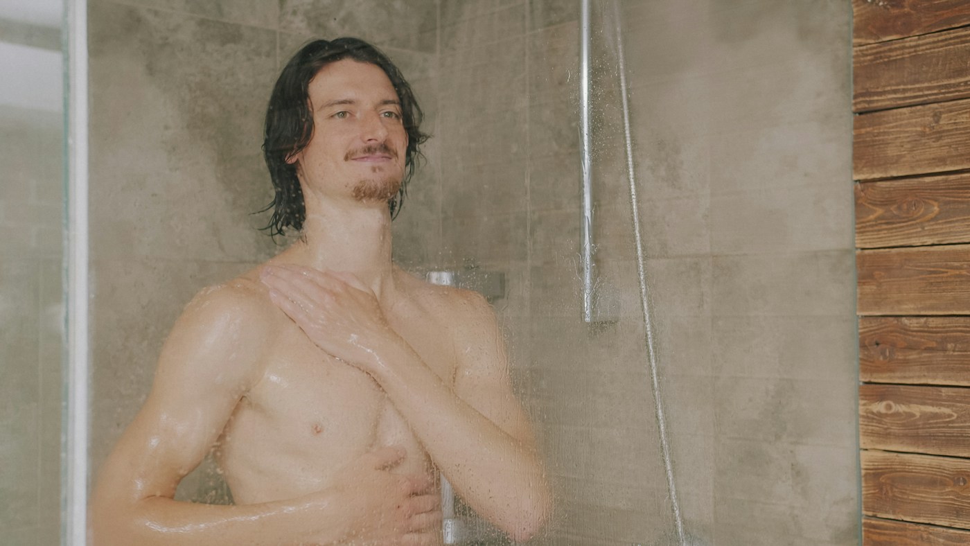 Person gently washing their upper body under a shower