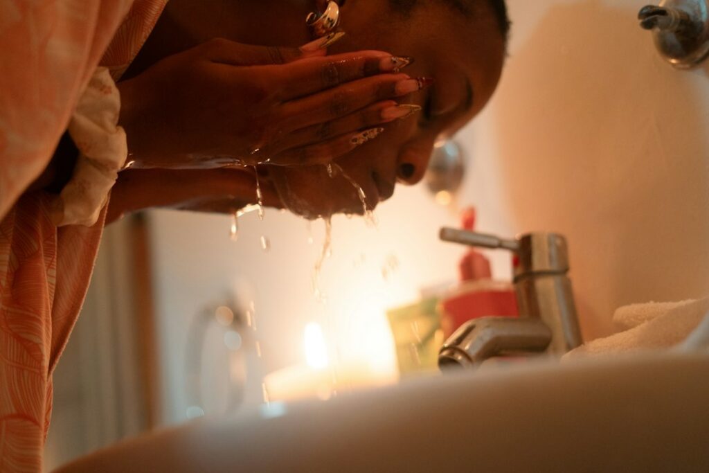 Woman washing face with a gentle cleanser at a bathroom sink