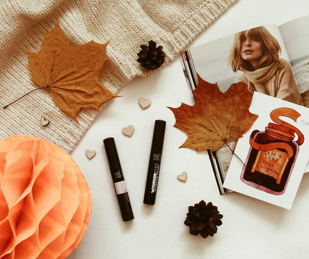 Lip balm and beauty essentials arranged in a warm autumn flat lay