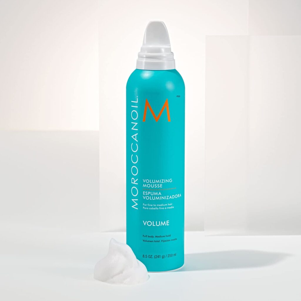 Turquoise Moroccanoil Volumizing Mousse can with a foam nozzle on a cream display pedestal