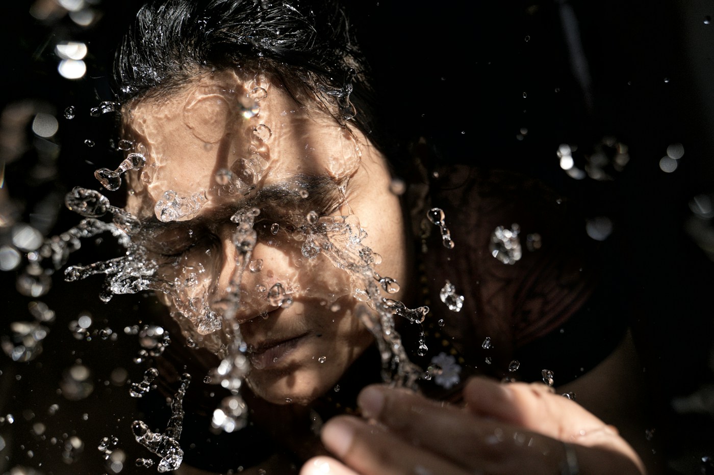 Person splashing water onto their face during a cleansing routine