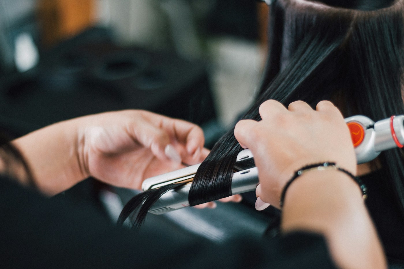 Stylist wrapping a small section of dark hair around a curling iron